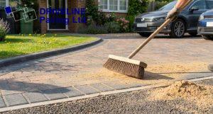 homeowner sweeping and re sanding block paving as a summer driveway maintenance tip