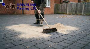 Kiln dried sand being brushed into the joints of cleaned block paving to prevent weed regrowth