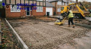 Excavated driveway with freshly compacted crushed stone sub-base and new concrete haunched edge restraints