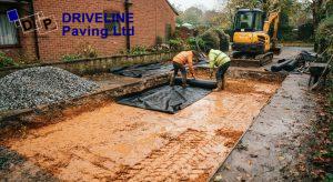 Geotextile membrane laid over wet clay sub-grade in an excavated driveway before the stone sub-base