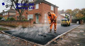 Hot tarmac being raked and rolled on a domestic driveway on a cool autumn morning in Essex